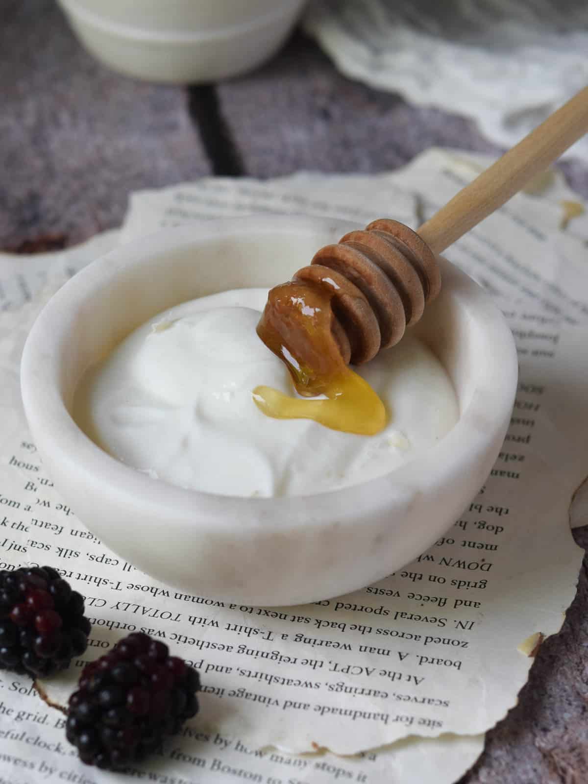 Plain blended cottage cheese with honey in a whit marble bowl.