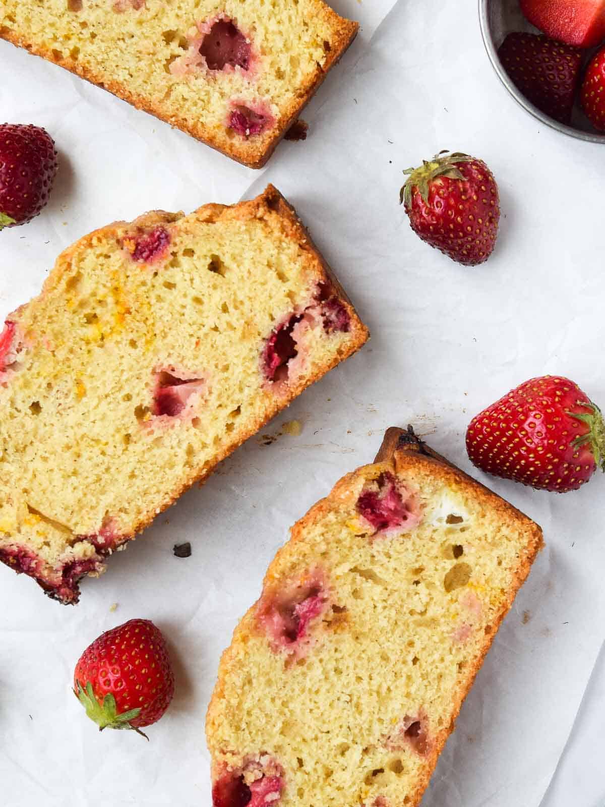 Slices of strawberry bread spread out on wax paper.