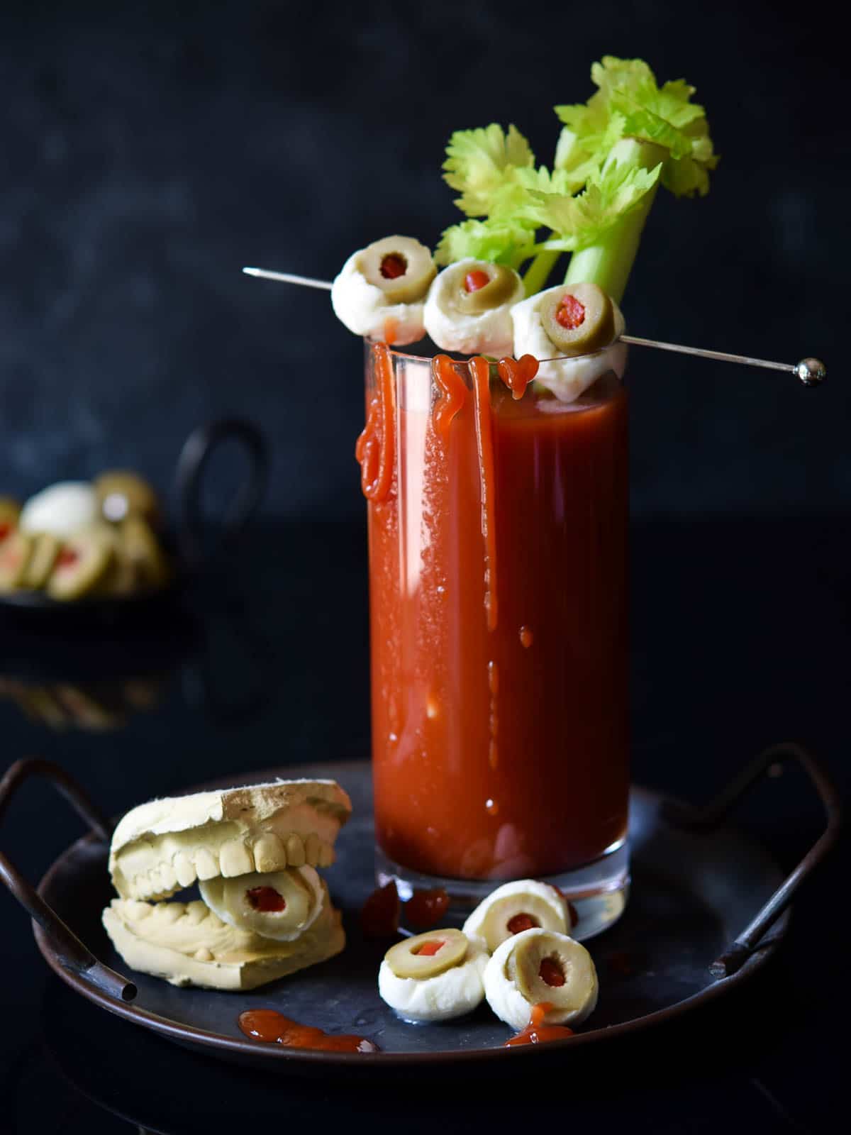 Bloody Mary with celery and mozzarella garnish on a black background.