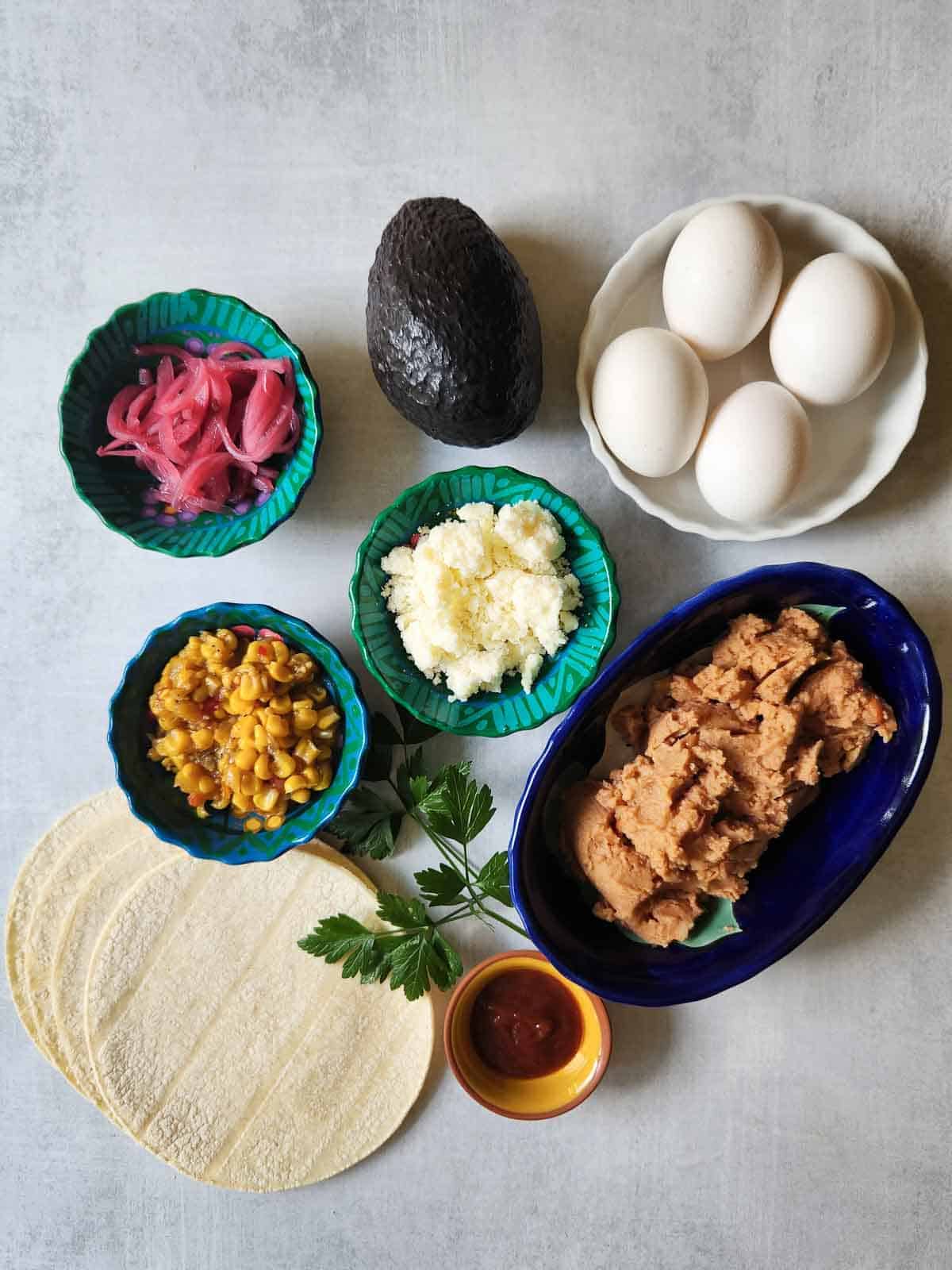 Overhead of ingredients in bowls for Mexican tostadas.