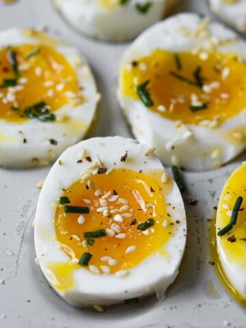 Soft-boiled eggs with sesame oil and toasted sesame seeds cut open.