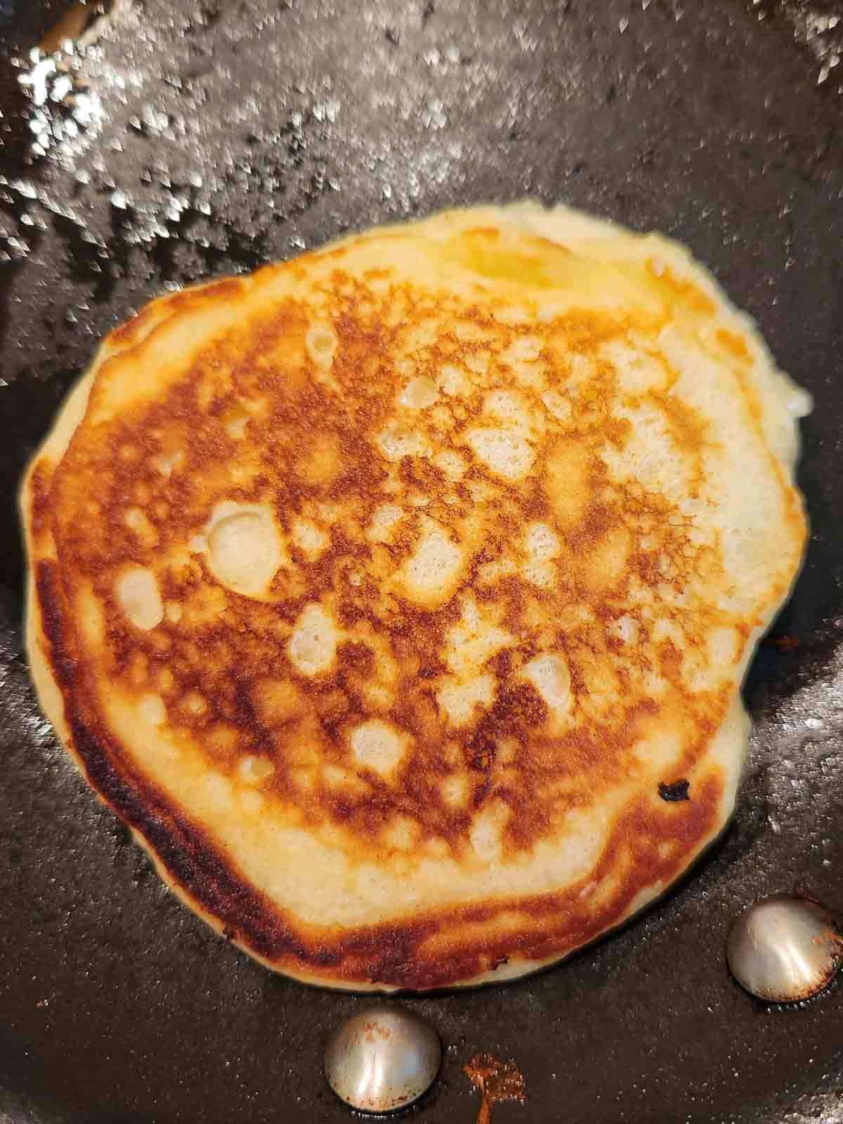 Lemon mascarpone pancake in a skillet that was just flipped with crispy edges.