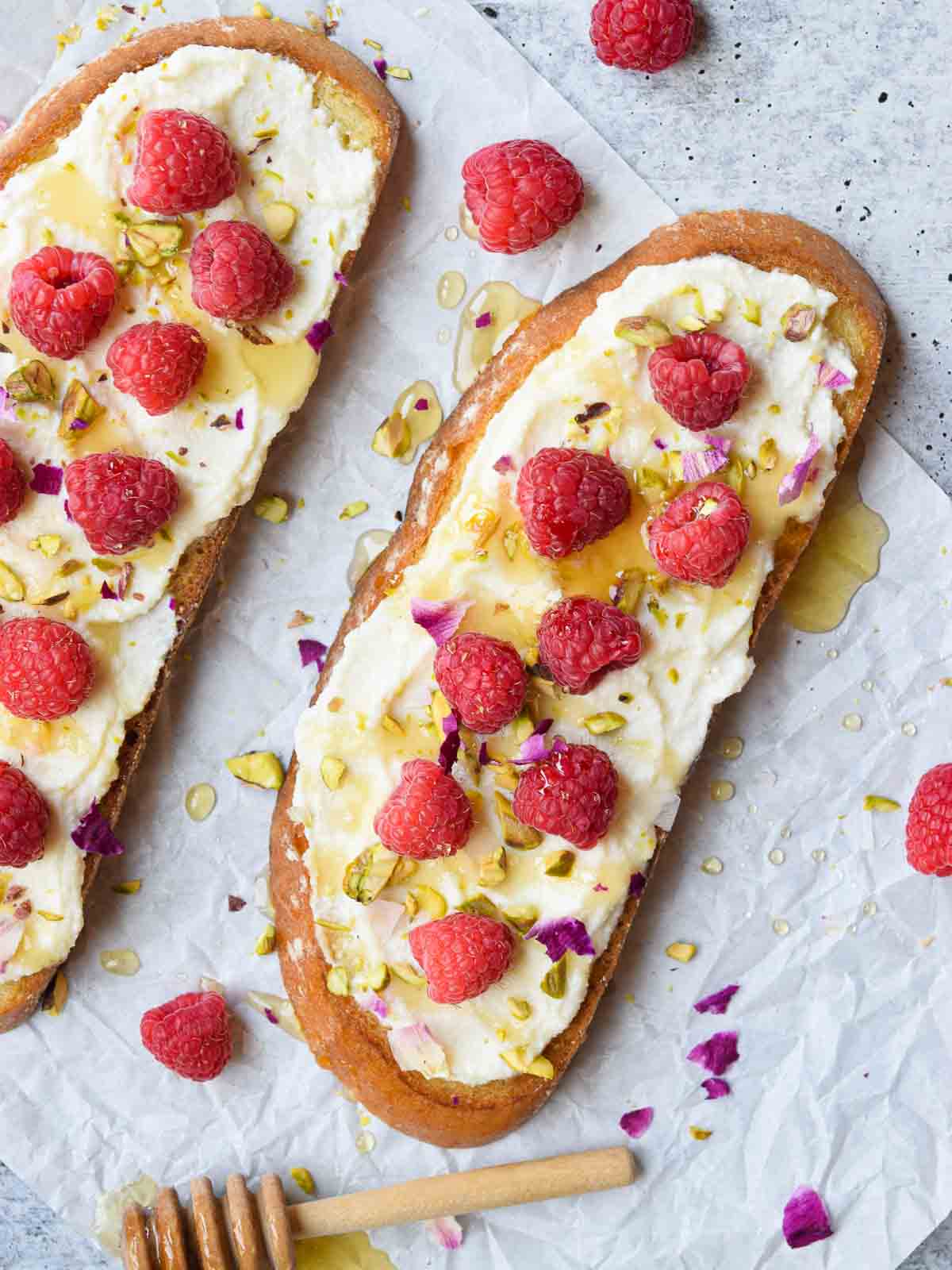 Overhead and close-up view of lemon ricotta raspberry toast on a concrete surface.