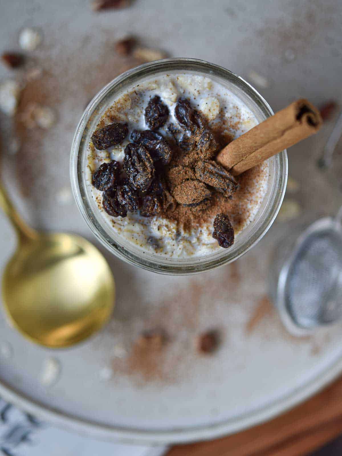 Overhead view of overnight oats in a jar with raisins and a cinnamon stick.
