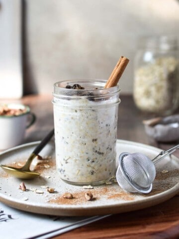 Eye-level view of overnight oats in a jar on a wood surface with the Sunday paper showing.
