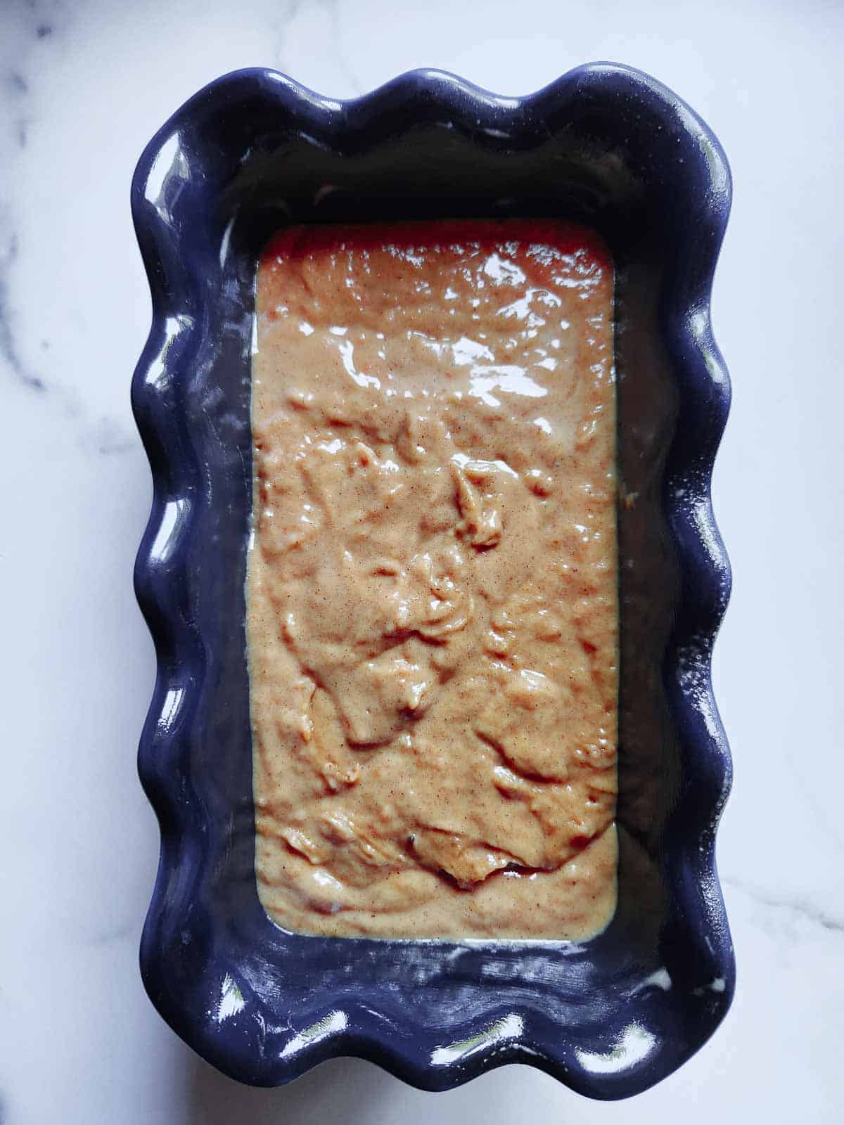 Prepared pumpkin bread batter in a blue loaf pan.