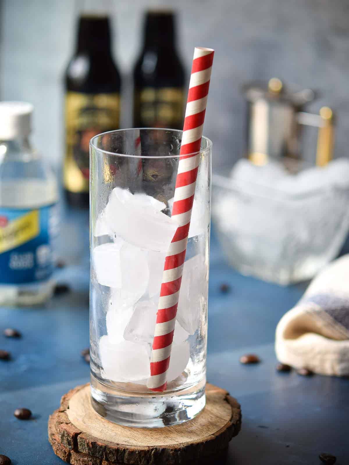 Clear glass with ice and a red straw.