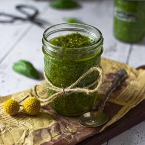 Roasted garlic pesto sauce in a clear jar on a wooden surface.