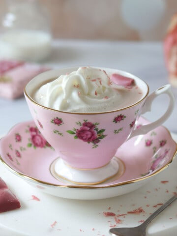 Ruby hot chocolate in a pink floral cup with whipped cream on top.