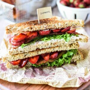 View of strawberry balsamic BLT on a wood board stacked on top of each other.