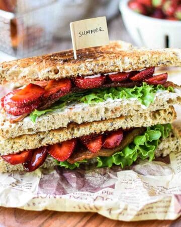 View of strawberry balsamic BLT on a wood board stacked on top of each other.