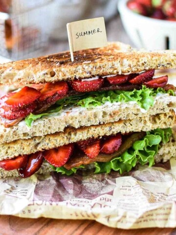 View of strawberry balsamic BLT on a wood board stacked on top of each other.