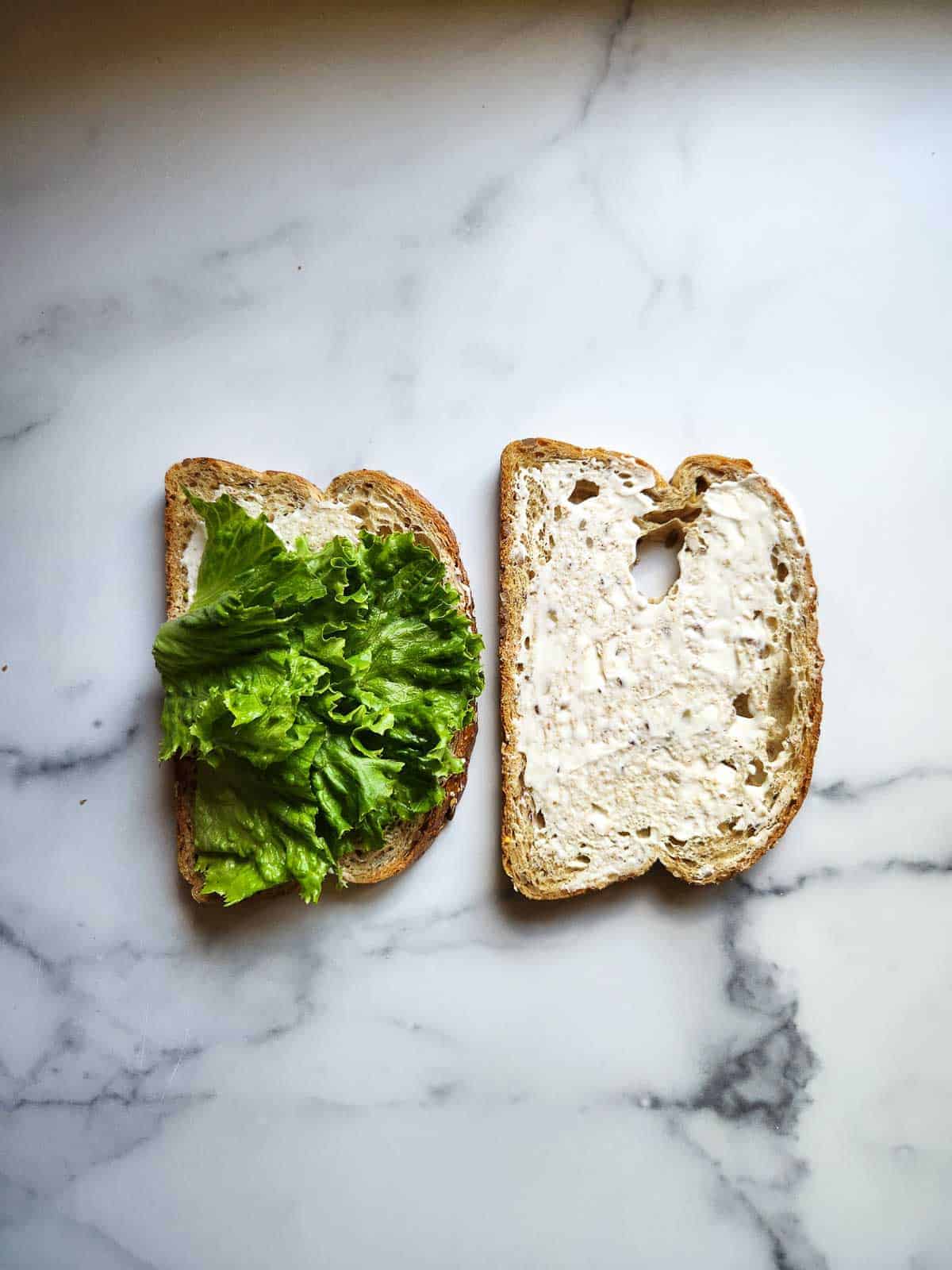 Assembling a BLT with mayo, lettuce and bread shown.