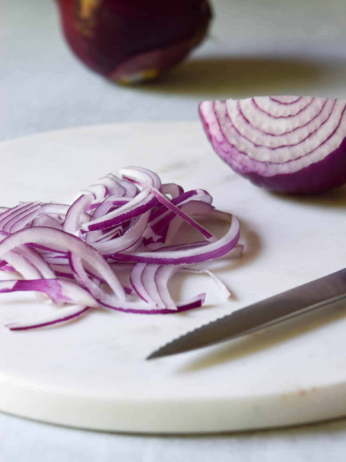 Sliced red onions on a marble cutting board.