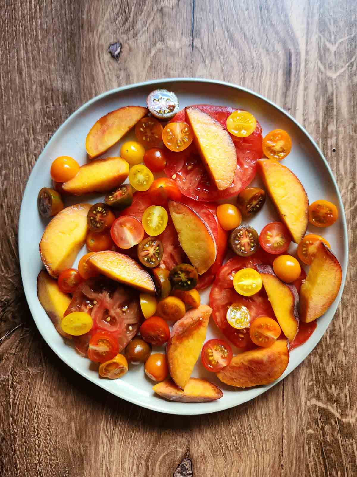 Tomatoes and peaches on a salad plate.