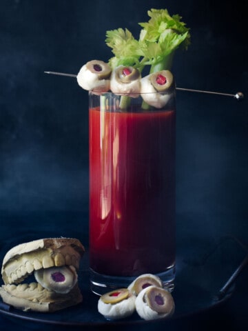 Bloody Mary with celery and mozzarella garnish on a black background.