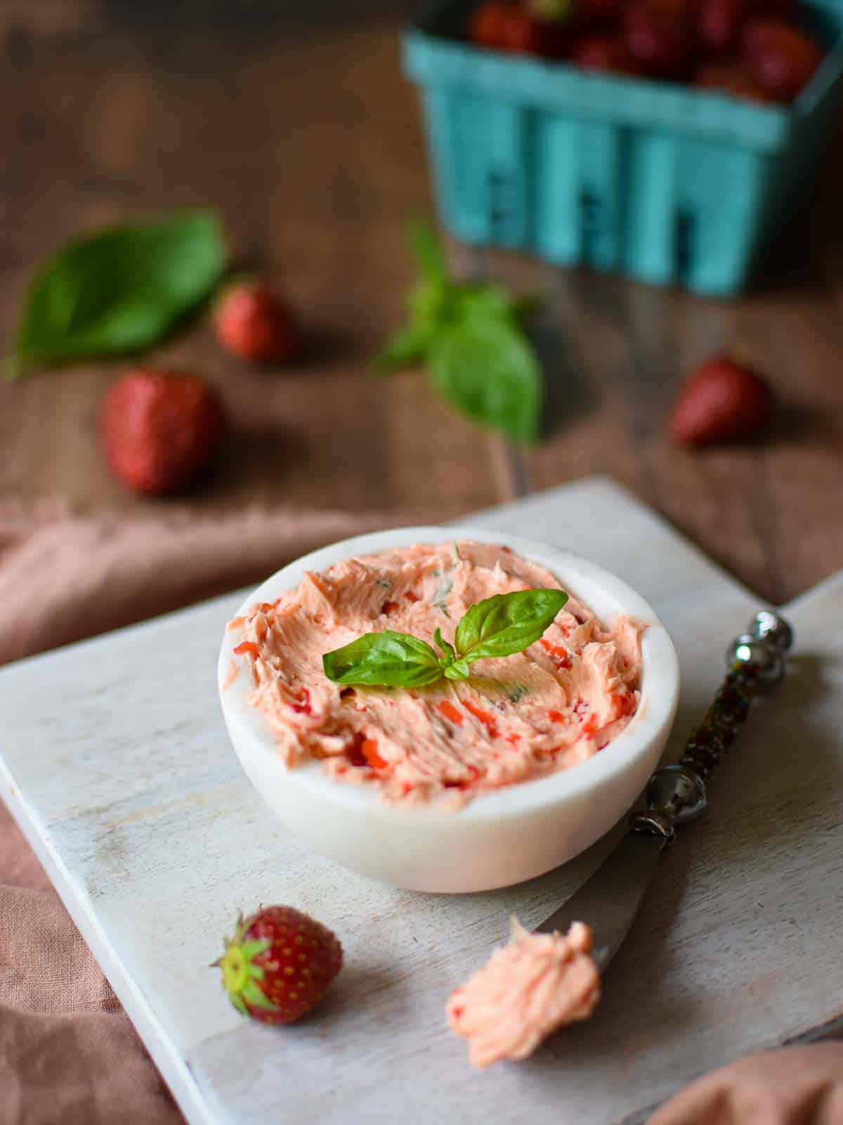 Whipped strawberry butter in a white bowl on a wooden background.