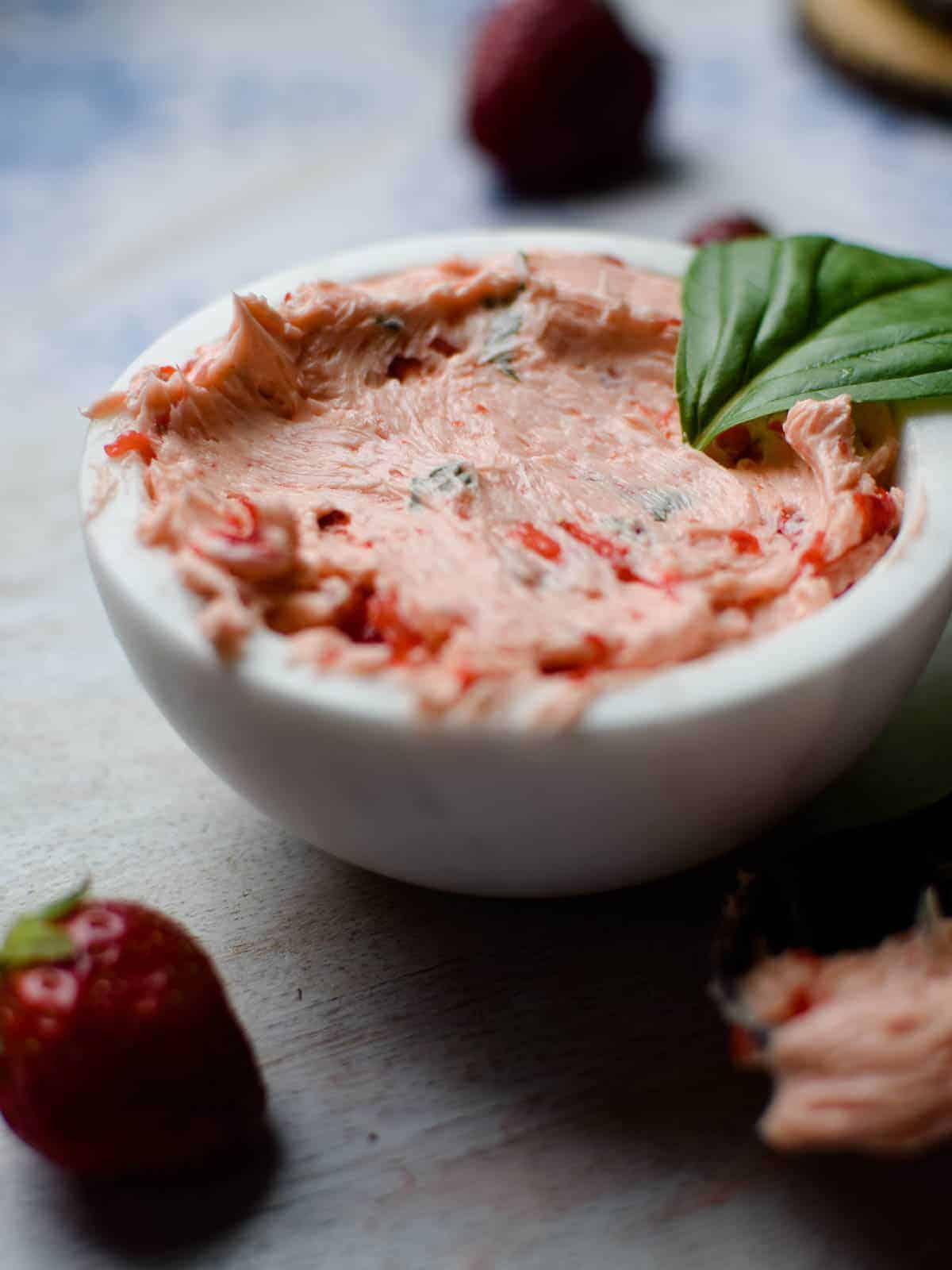 Close-up of whipped strawberry and basil butter in a white bowl.