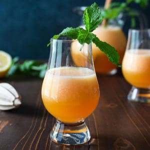 Eye level view of canteloupe lime agua fresca on a wooden background with mint in the glass