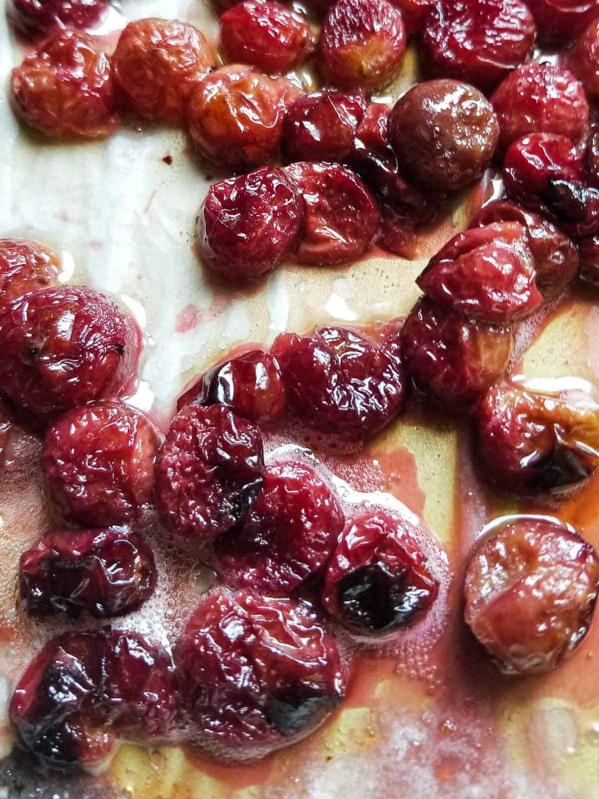 Over head view od oven roasted red grapes right out of the oven on a pan lined with parchment paper
