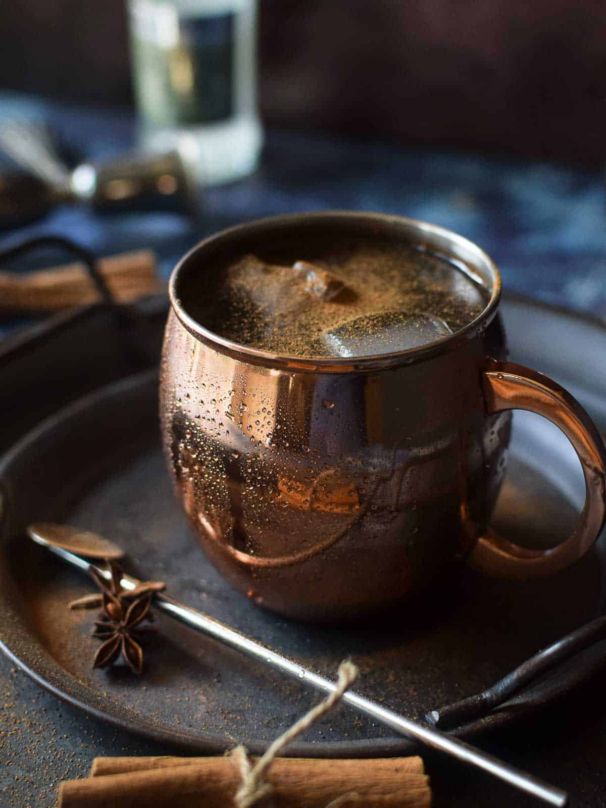 Close up of chai moscow mule in a copper mug with cinnamon stick and whole anie.