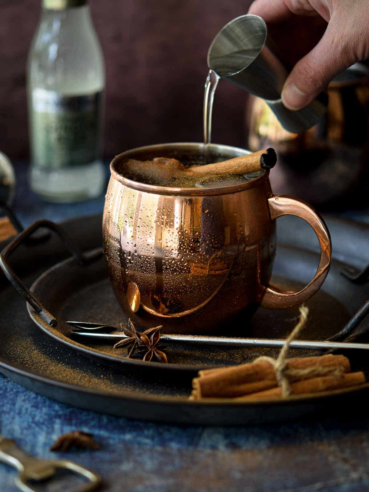 Chai Moscow mule in a copper mug with vodka being poured in.