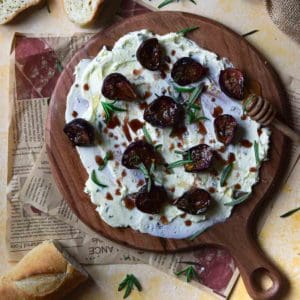 Overhead view of roasted figs on a serving board with butter.