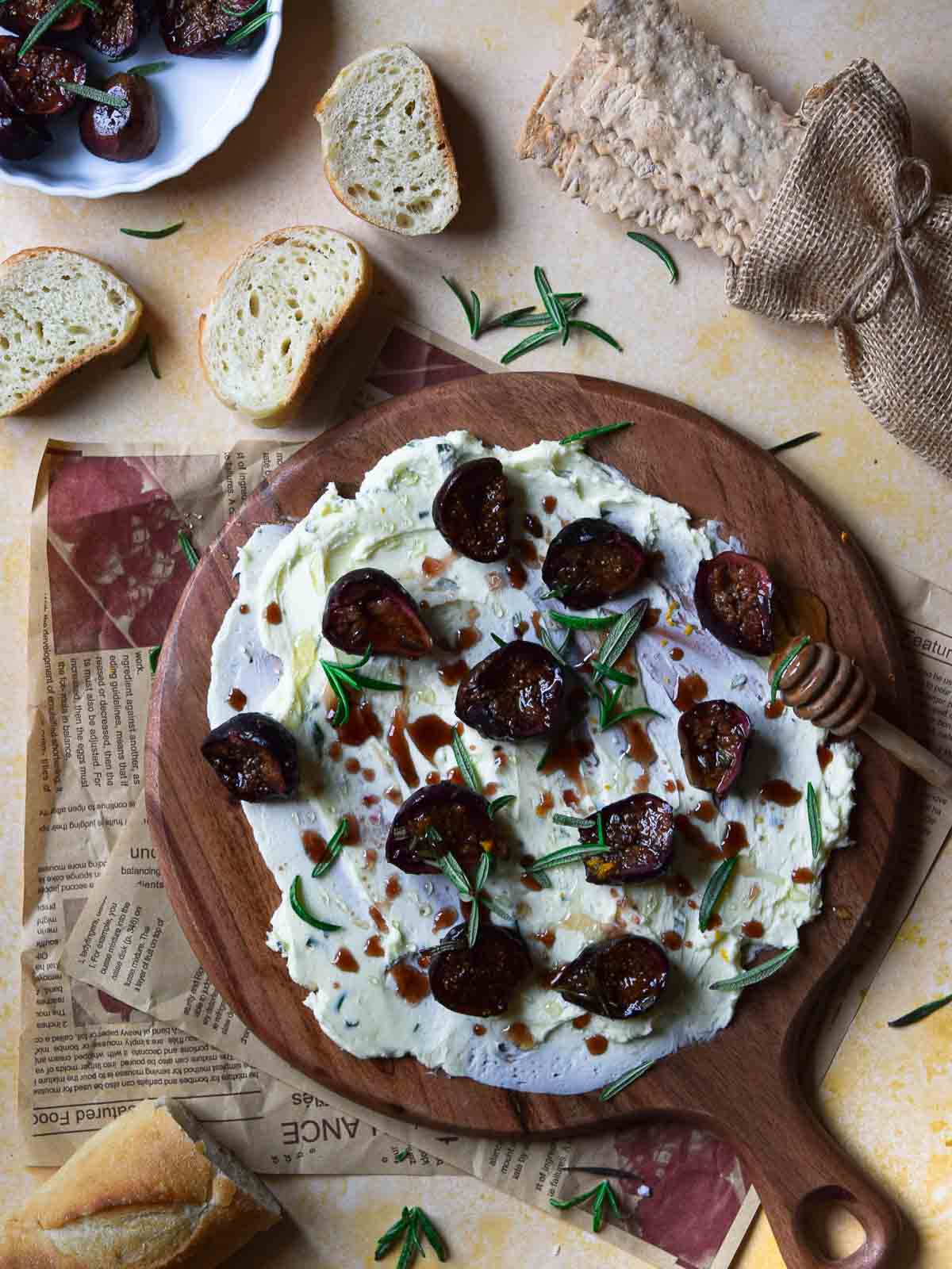 Overhead view of roasted figs on a serving board with butter.