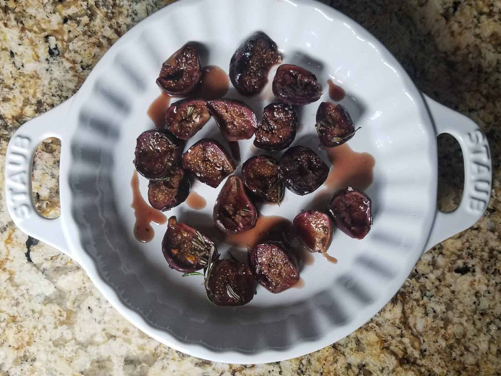 Roasted figs out of the oven in a white baking pan.