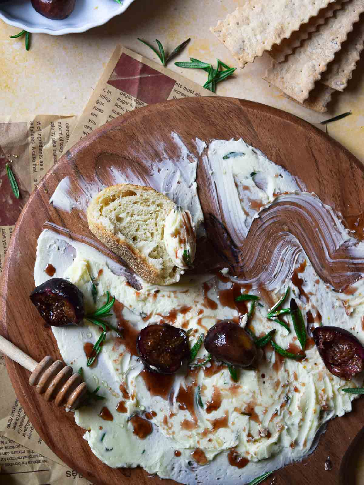 Overhead view of roasted figs and bread on a serving board with butter.
