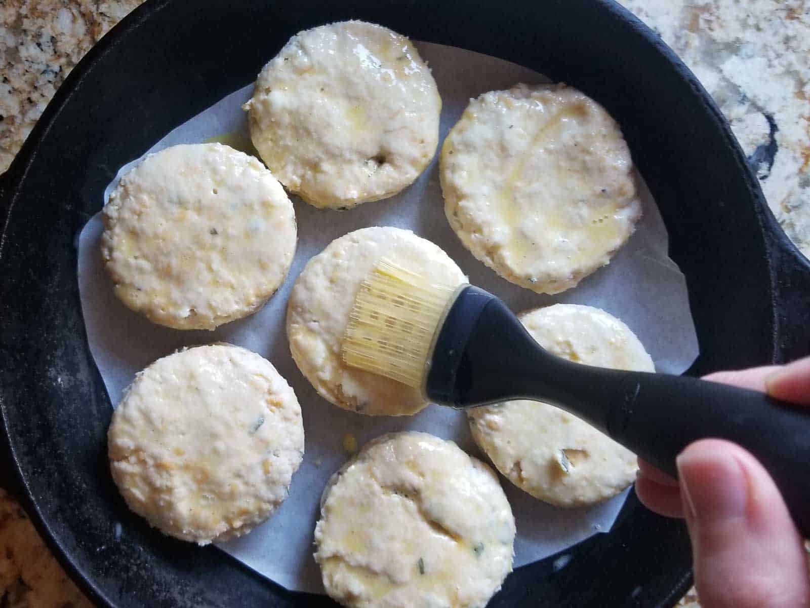 Cut biscuits getting and egg wash and placed in a cast iron skillet ready for baking.