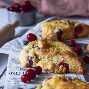 Angled view of cranberry orange scones on a cooling rack with scattered cranberries.