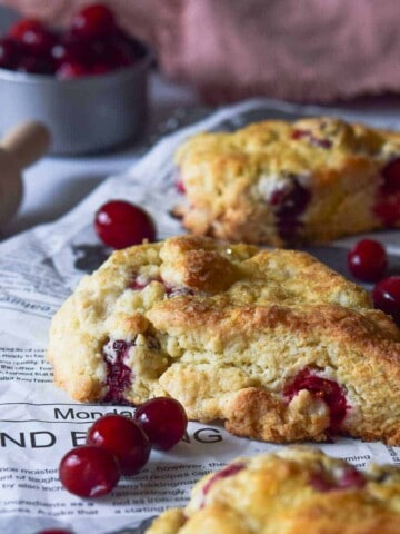 Angled view of cranberry orange scones on a cooling rack with scattered cranberries.