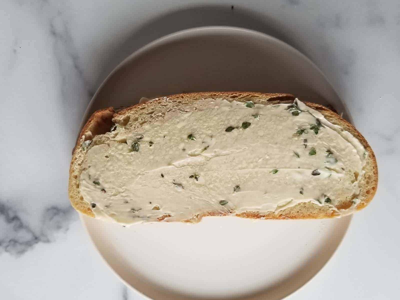 Bread spread with thyme butter ready to be grilled.