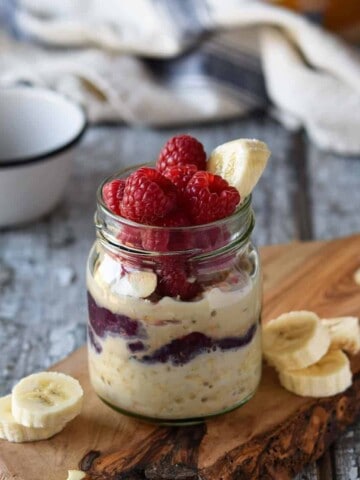 Peanut butter overnight oats in a jar with raspberries and bananas.