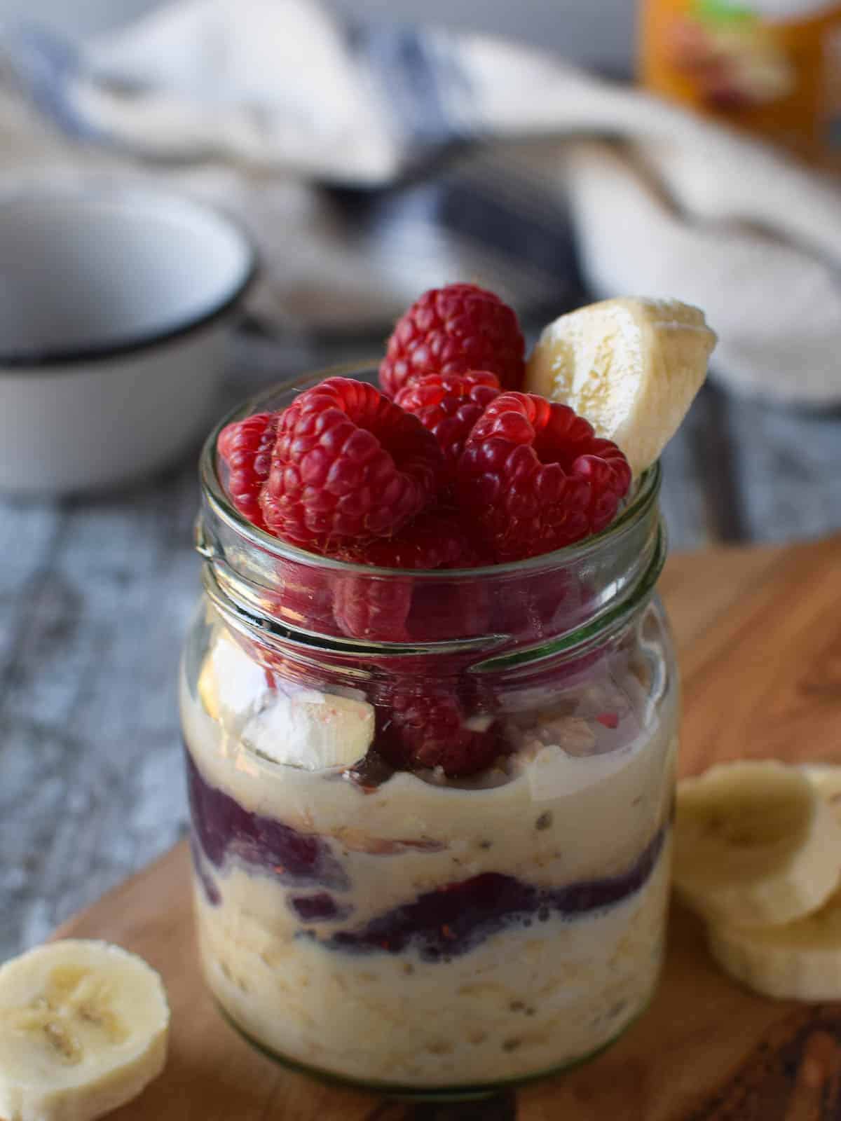 Close-up of peanut butter overnight oats in a jar with raspberries and bananas.