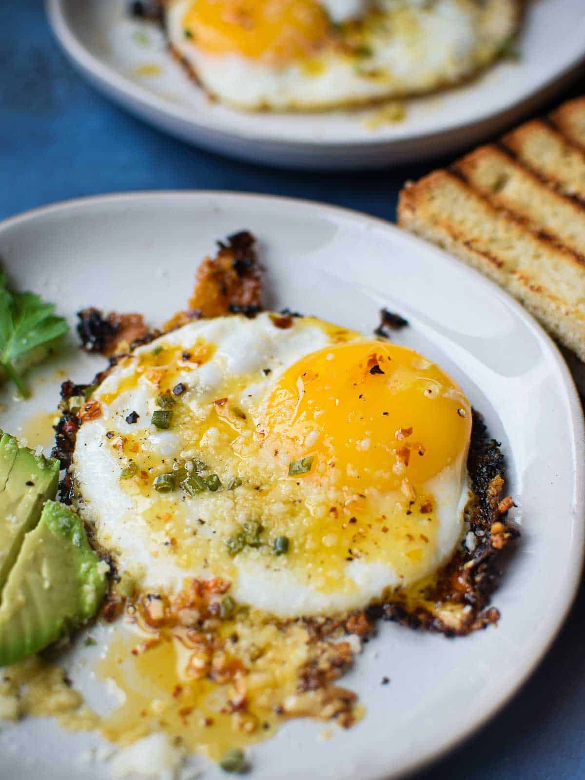 Fried egg on a white plate with chili crisp on top.