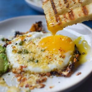 Fried egg with bread being dunked in a runny yolk.