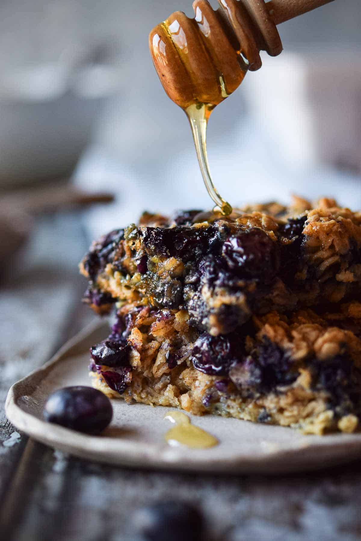 Honey is drizzled over a slice of blueberry-baked oatmeal.