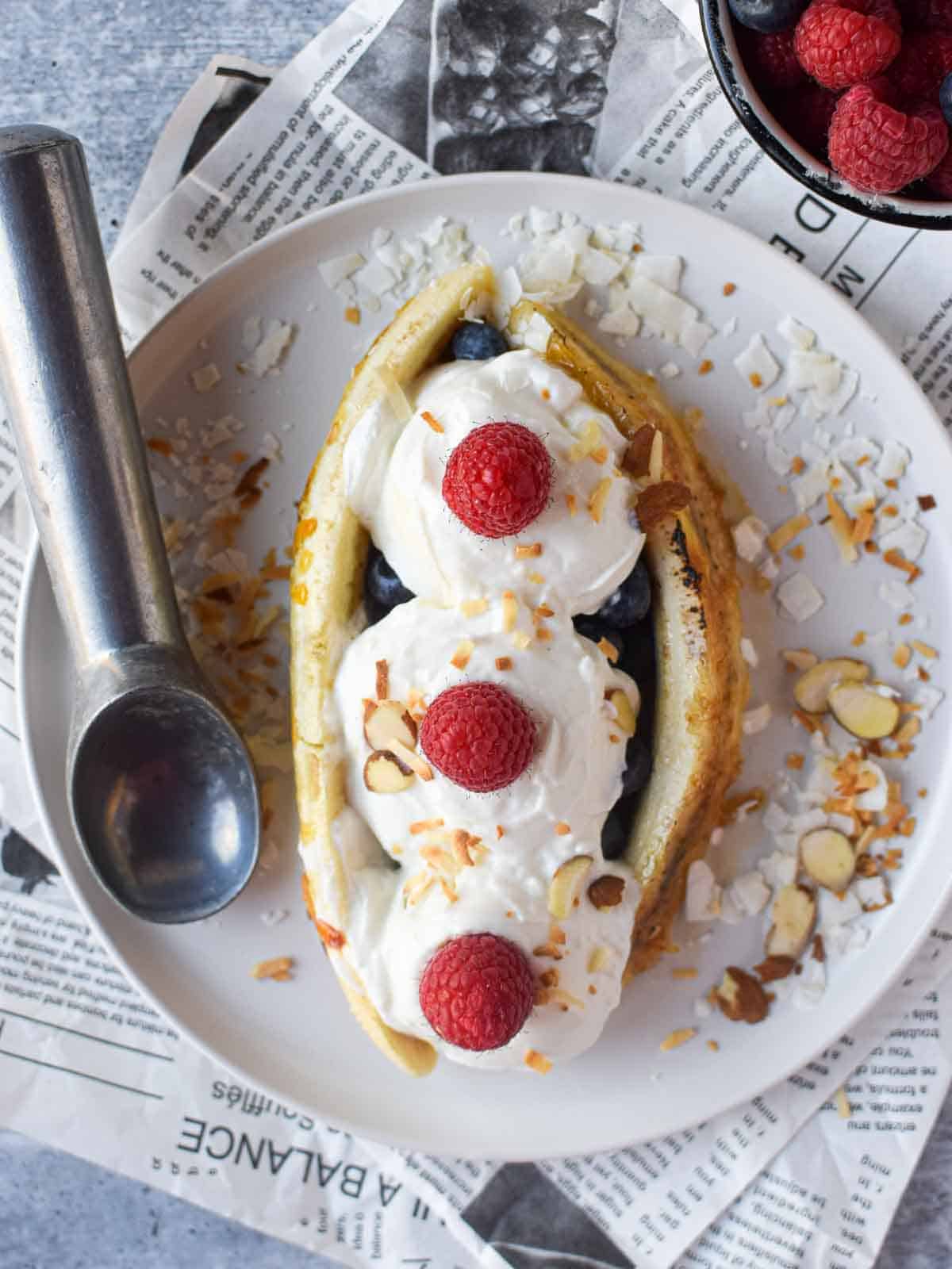 Overhead breakfast banana split with yogurt with fresh fruit and nuts.