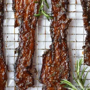 Candied bacon with rosemary on a wire rack.
