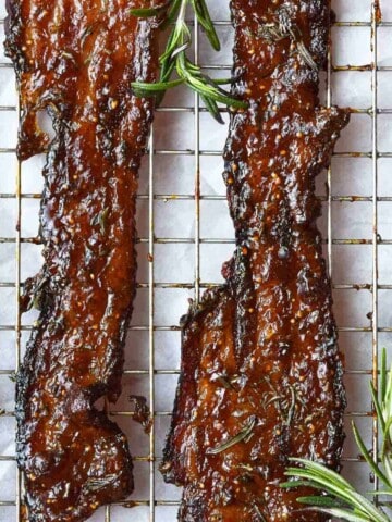 Candied bacon with rosemary on a wire rack.