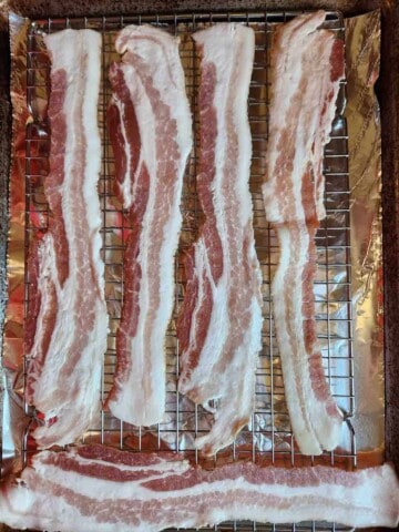 Raw bacon on a baking sheet.