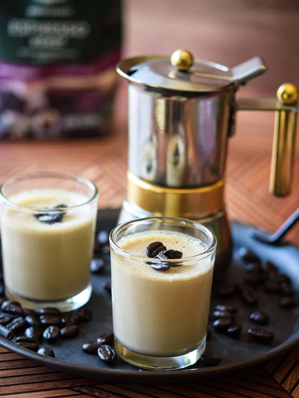 Espresso panna cotta in small glass jars with coffee in the background.
