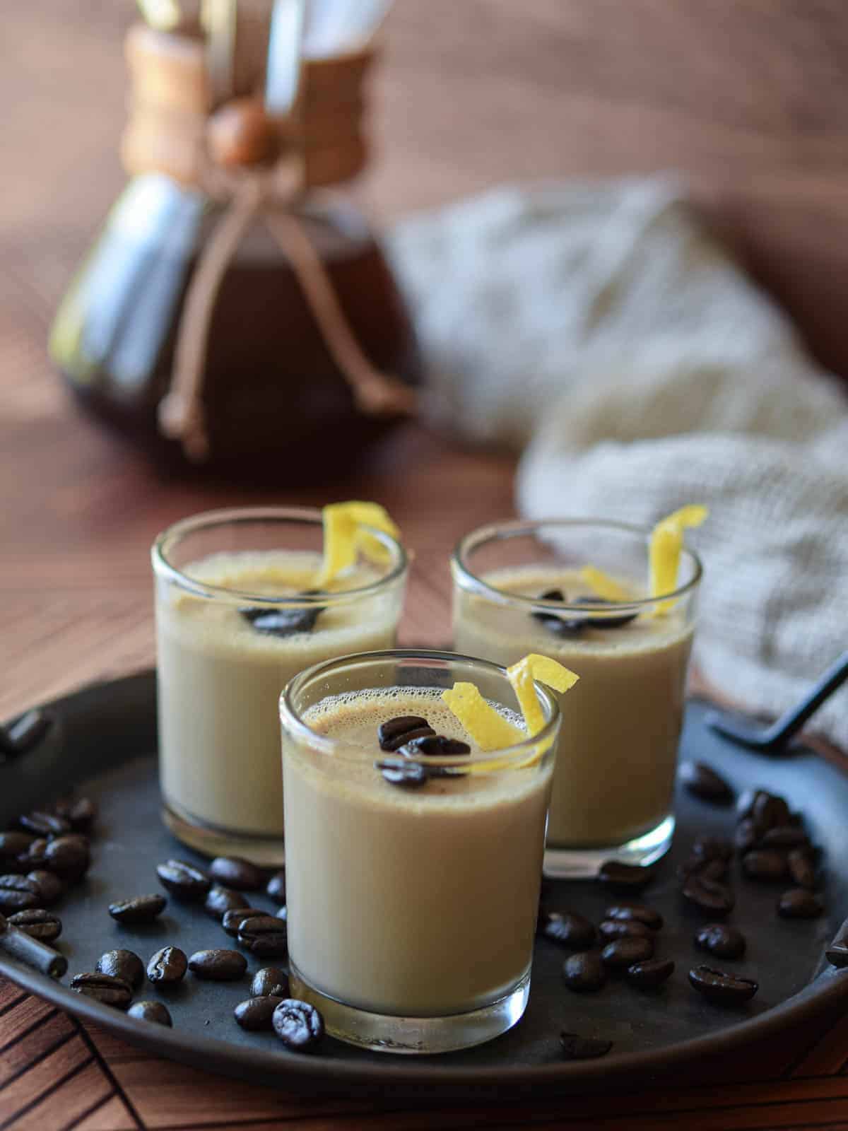 Espresso panna cotta in small glass jars with coffee beans and lemon rind twists.