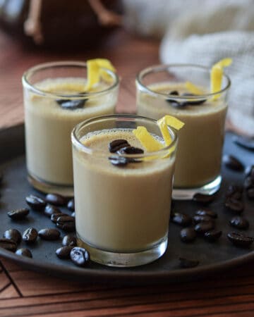 Espresso panna cotta in small glass jars topped with coffee beans and lemon rind.