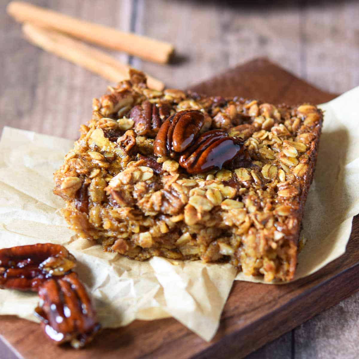 Slice of baked oatmeal with pecans on top with a brown background.