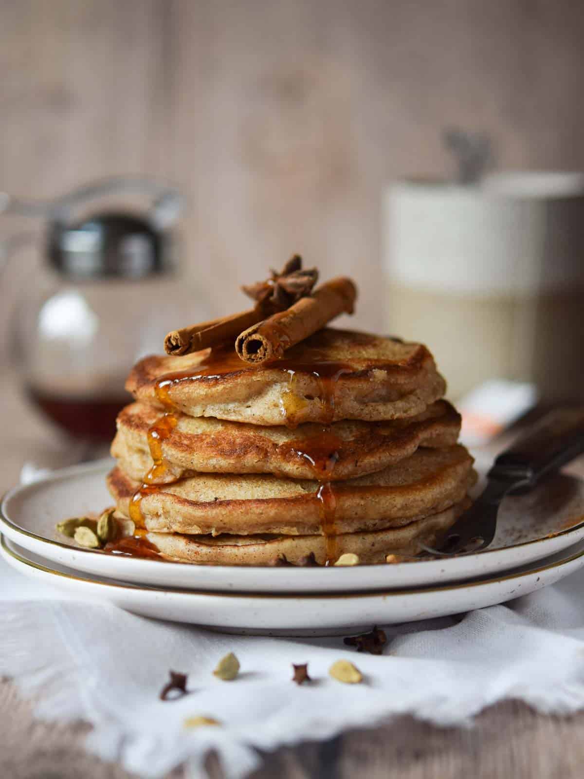 Chai pancakes stacked with cinnamon and maple syrup.