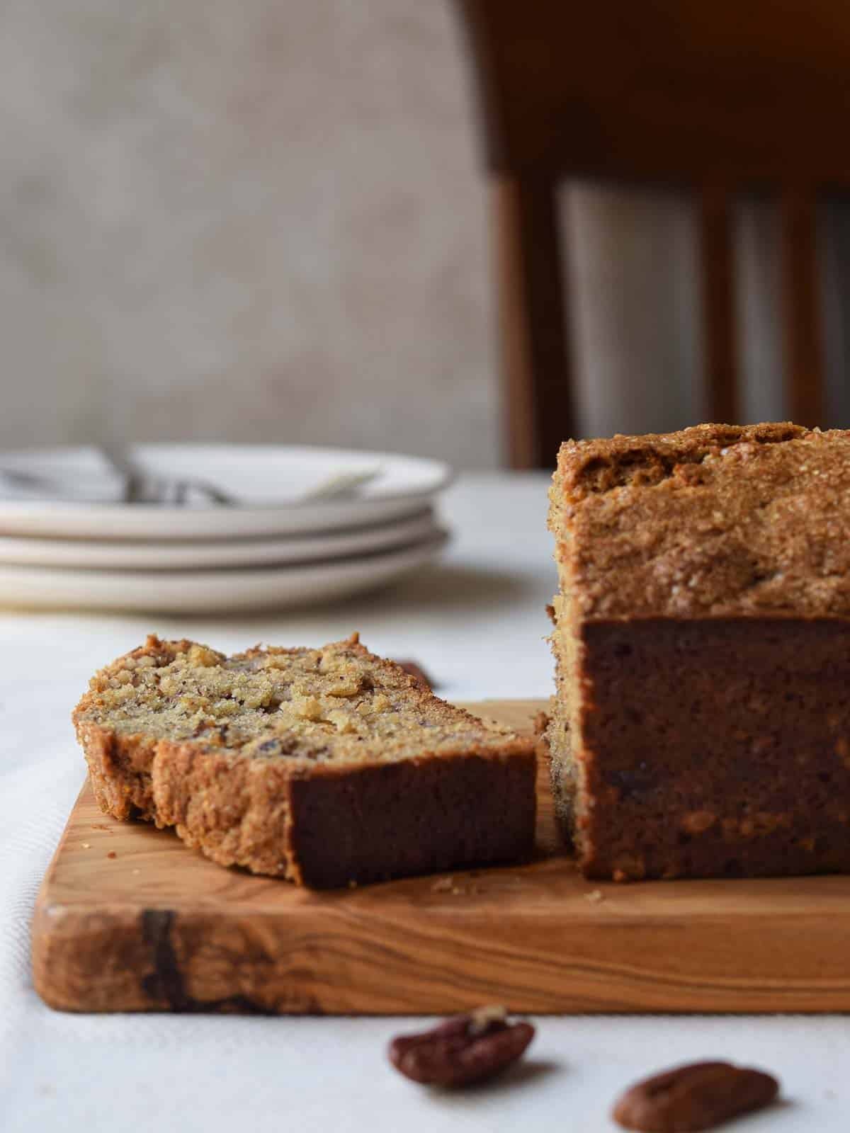 A slice of banana bread cut from a loaf on a kitchen table.