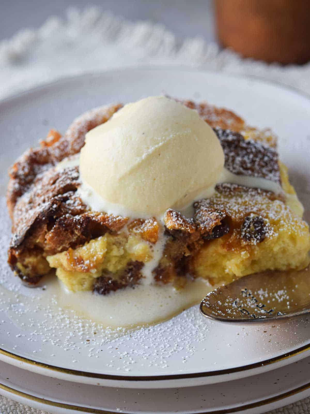 Close-up of panettone bread pudding with a scoop of vanilla ice cream on top.